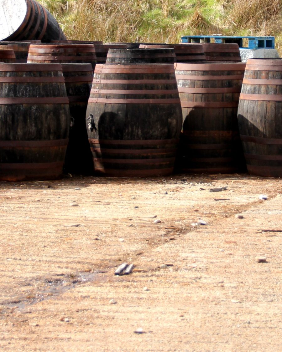 Row of weathered oak whiskey casks with rusted iron hoops