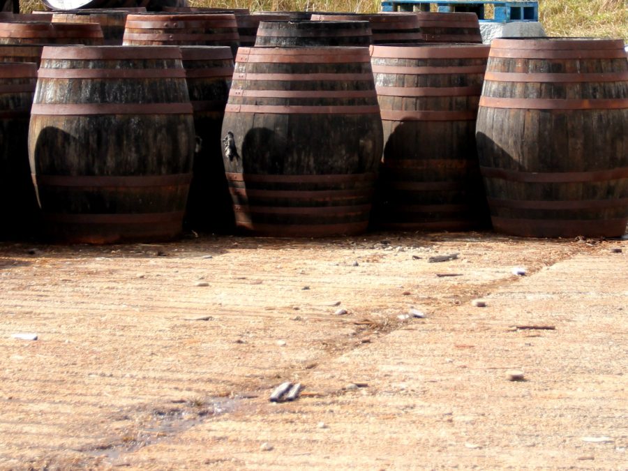 Row of weathered oak whiskey casks with rusted iron hoops