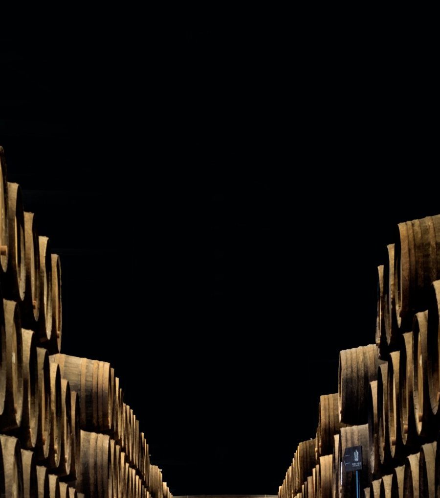 Rows of oak port pipes converging in a dim wine cellar