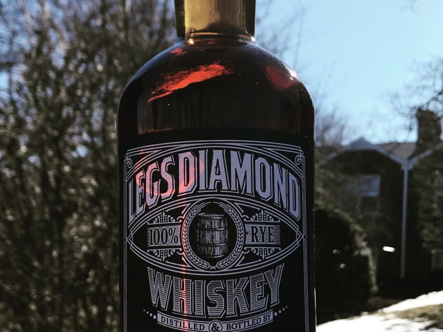Legs Diamond 100% rye whiskey bottle held up against winter sky