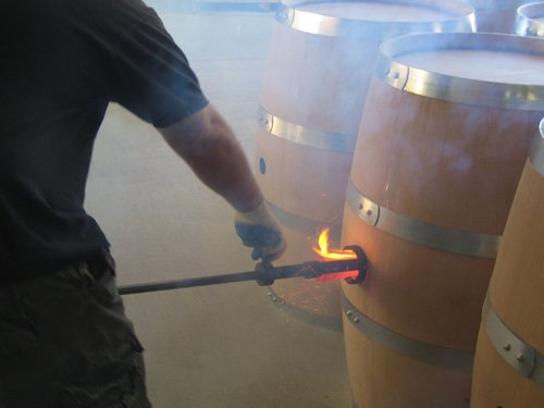 Cooper charring the inside of an oak barrel with an open flame