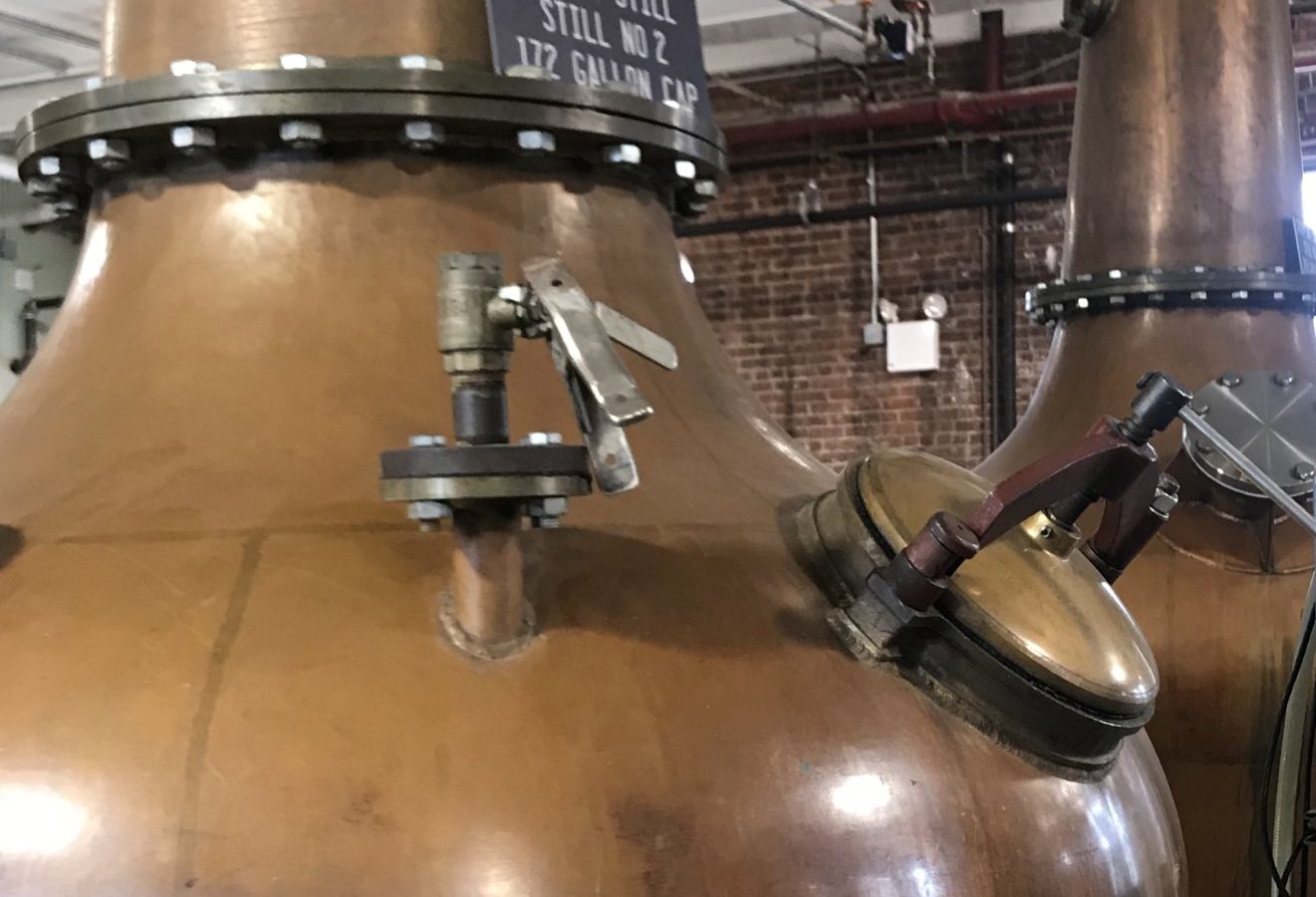 Close-up of a copper spirit still with a technical capacity placard